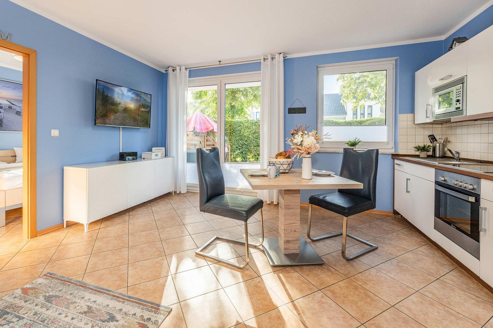 Kitchen and dining area with table, chairs, and TV on the wall.