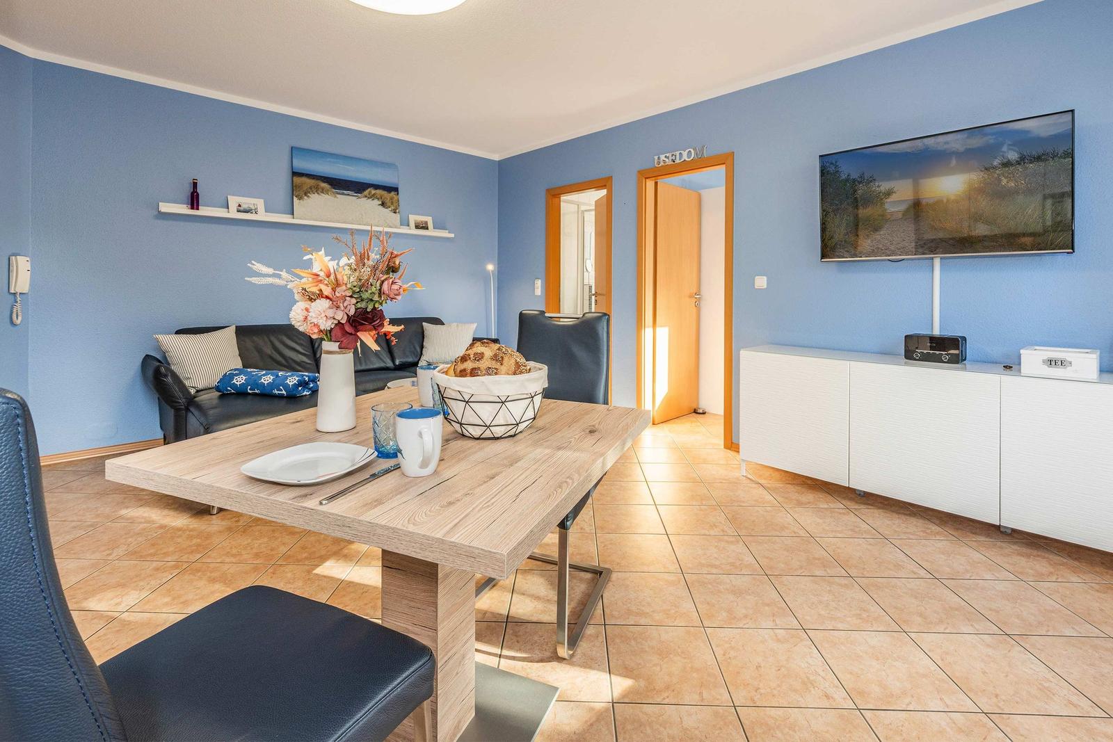 Living and dining area with blue walls, dining table, sofa, and TV.