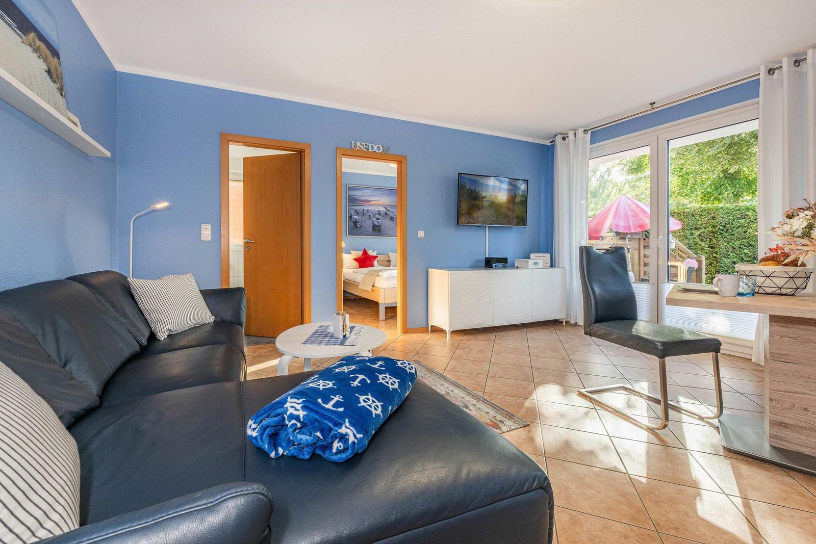 Living room with sofa, TV, and view of balcony