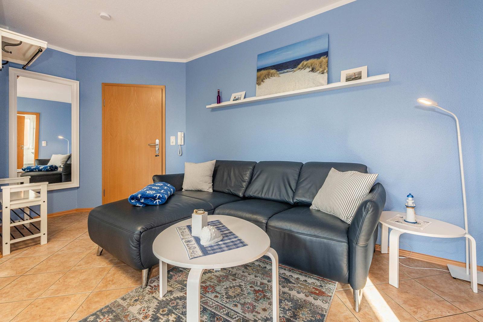 Living room with blue walls, black leather sofa, and round tables.
