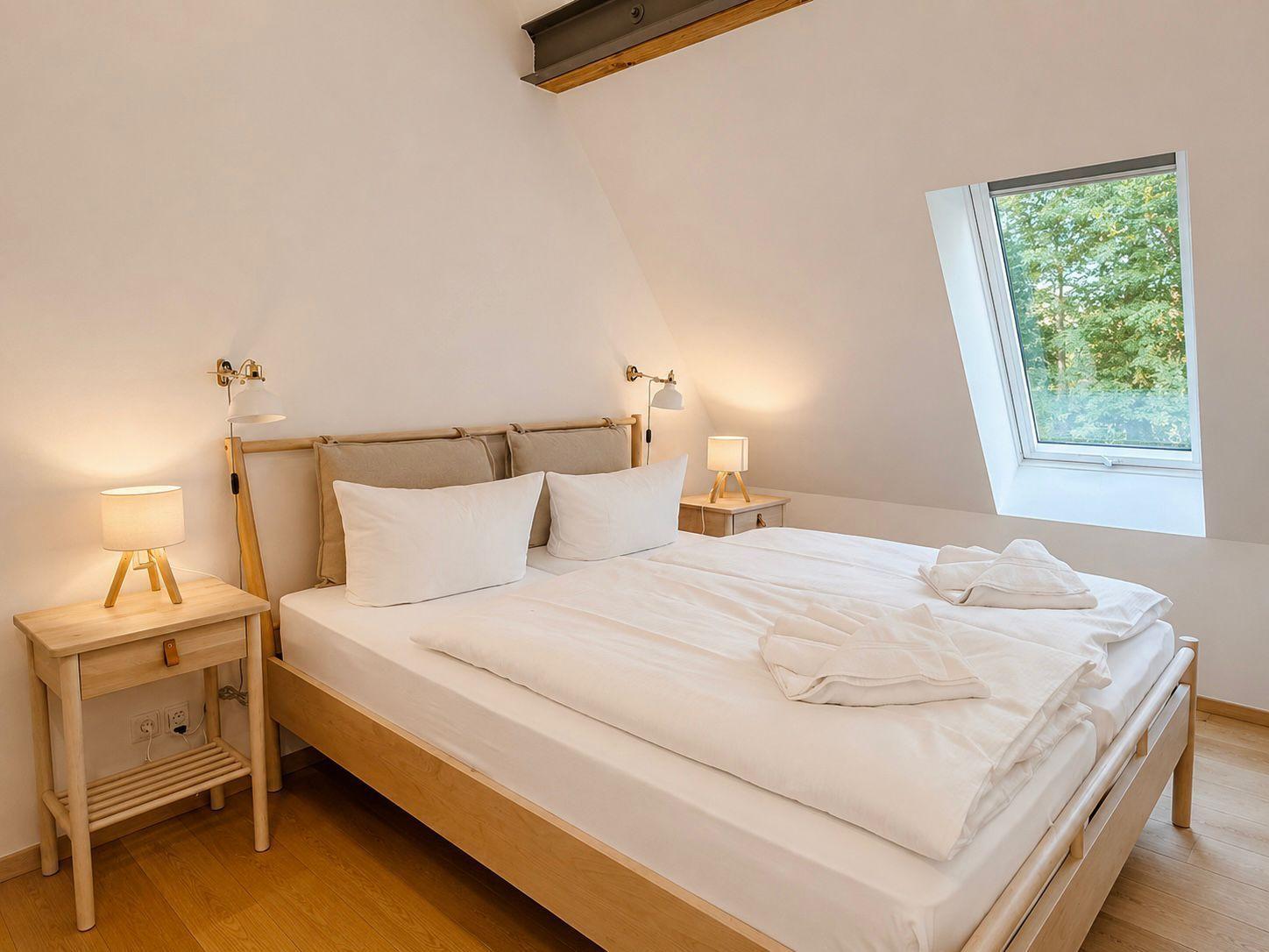 Ein Schlafzimmer mit Doppelbett, zwei Nachttischen und einem Dachfenster.
