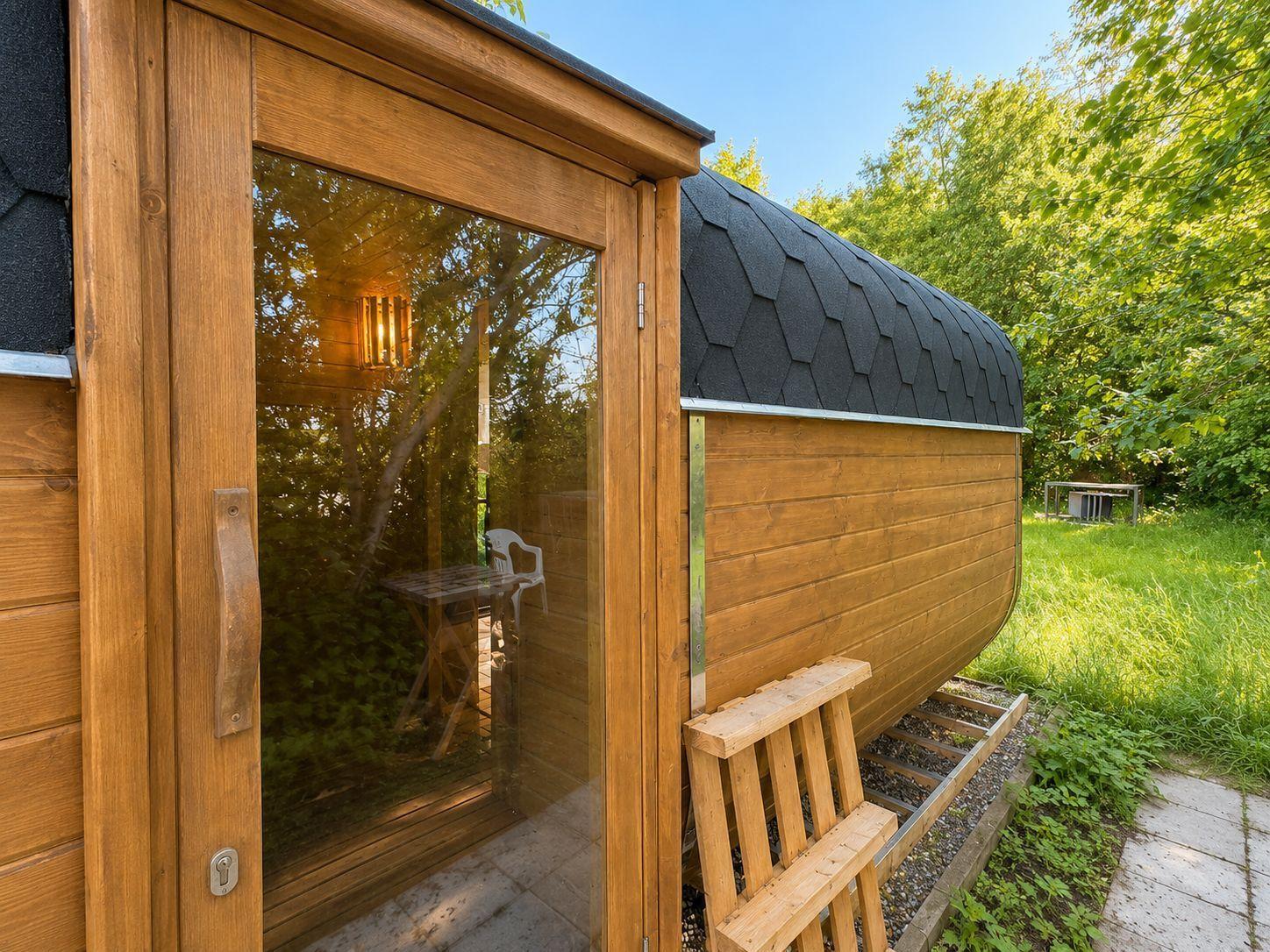 Holzsauna mit Glasfront und Außentreppe im grünen Garten