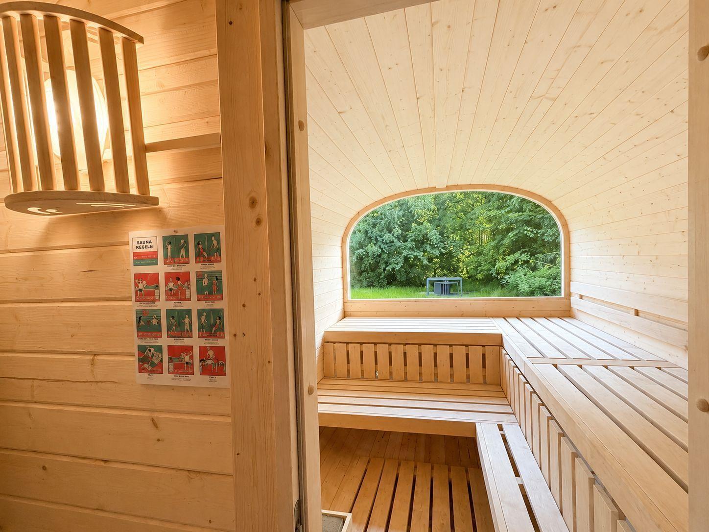 Sauna mit Holzbänken und Bogenfenster zum Garten
