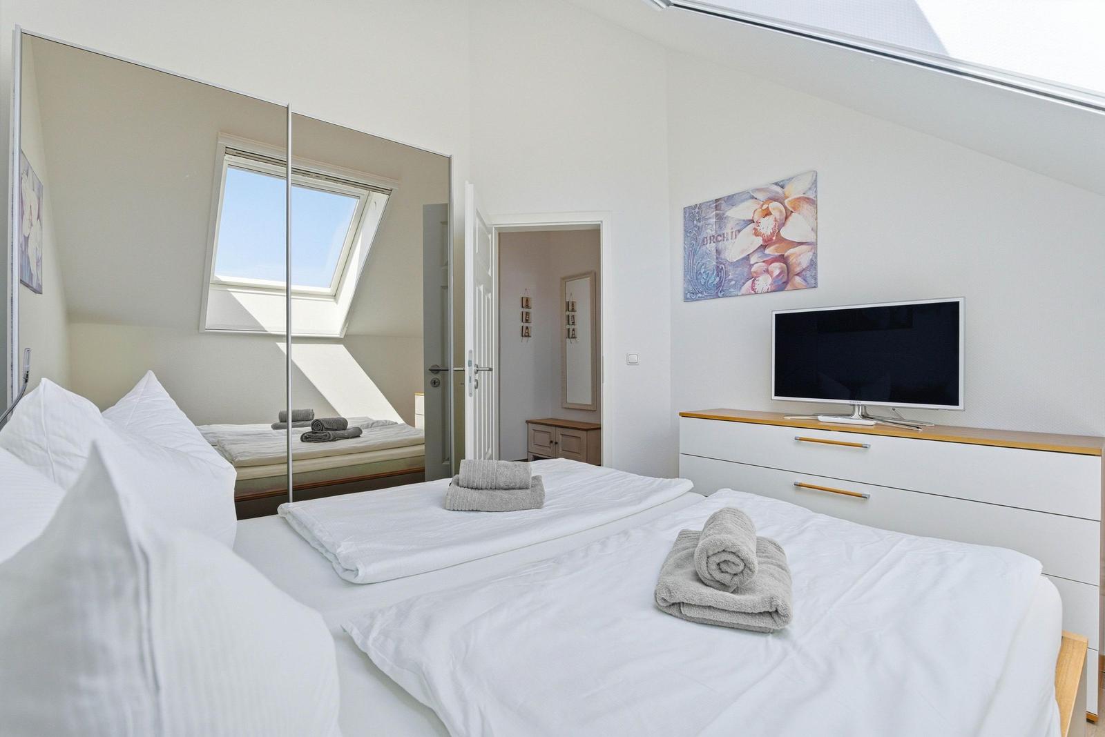 Schlafzimmer mit Doppelbett und TV