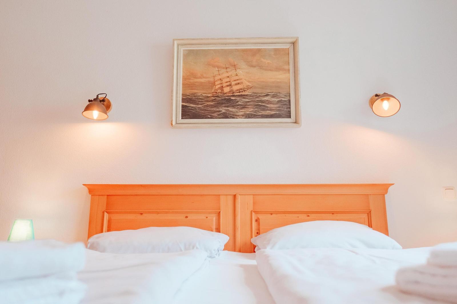 Schlafzimmer mit Holzbett, Wandbild und zwei Wandlampen.
