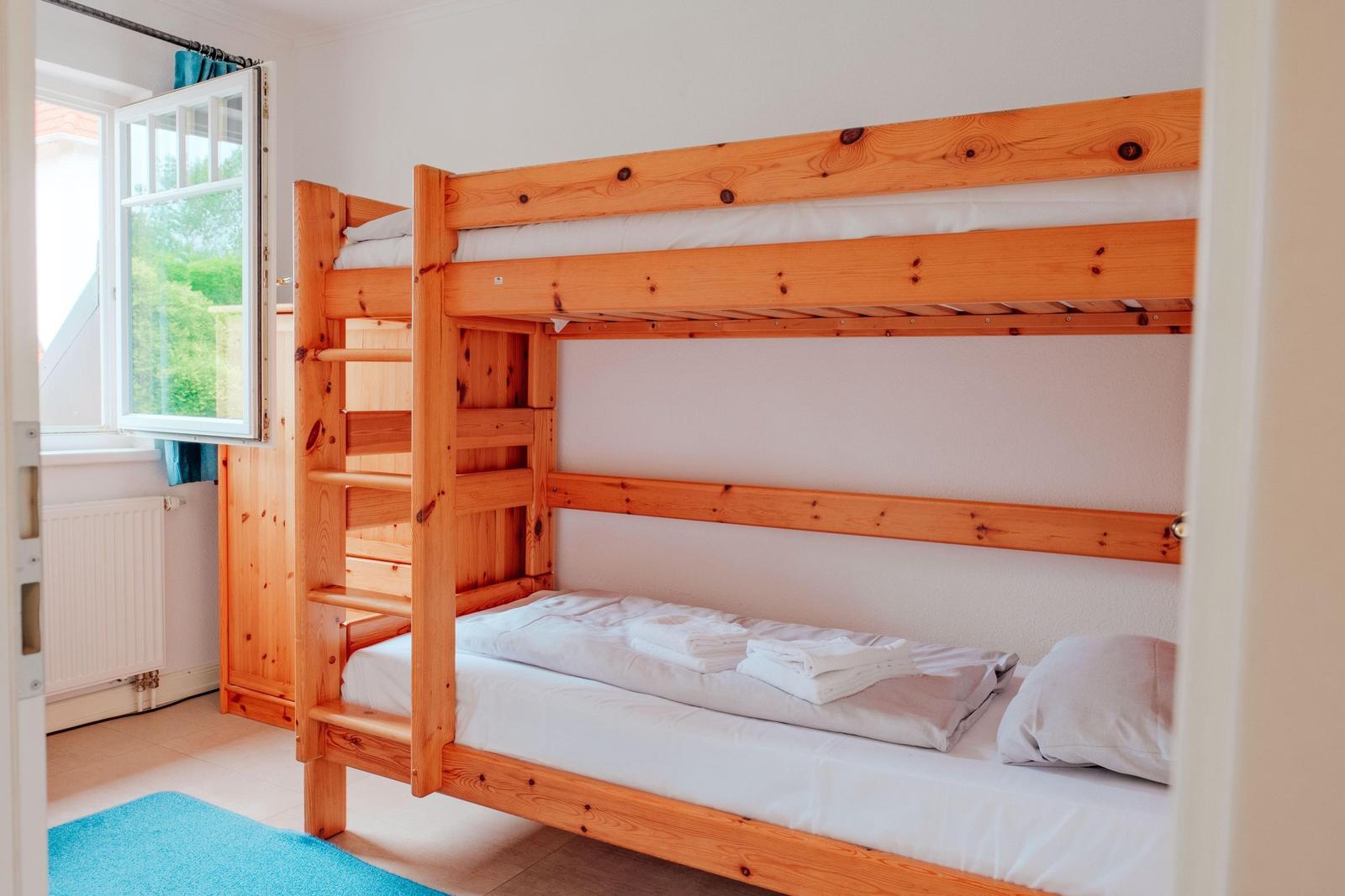 Zimmer mit Holz-Kojenbett, Fenster und Heizkörper