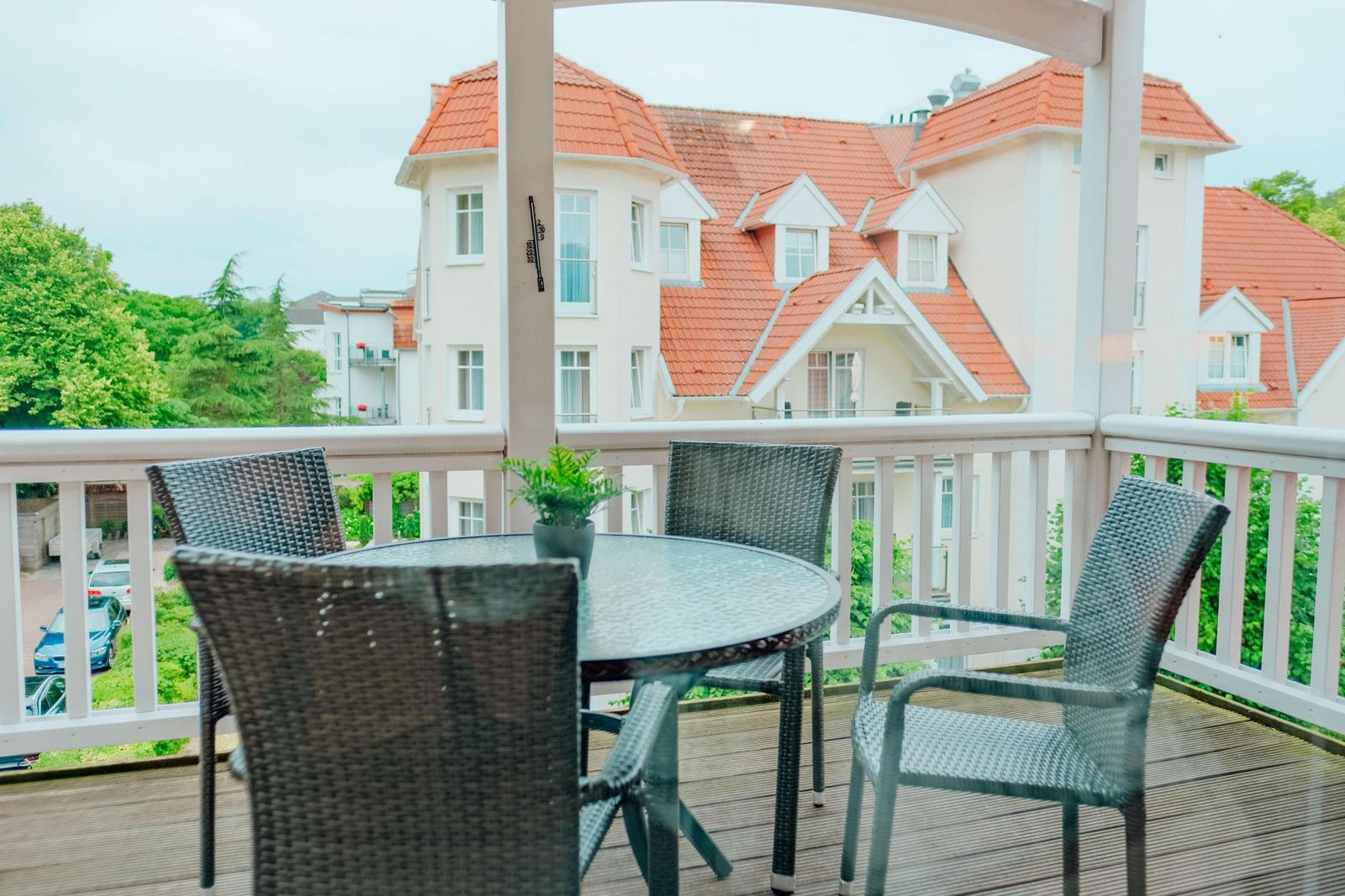 Terrasse mit Tisch und Stühlen. Blick auf ein Gebäude mit rotem Dach.