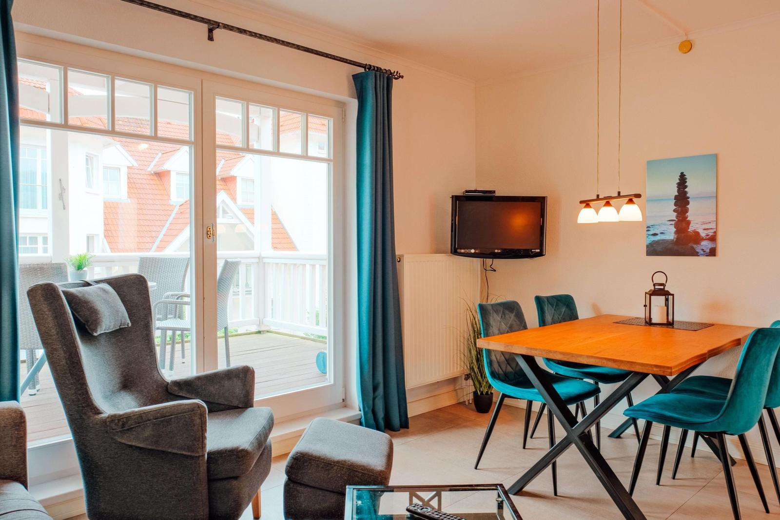 Wohn- und Essbereich mit Sitzgelegenheit, Tisch und TV. Balkon mit Sicht auf Dächer.