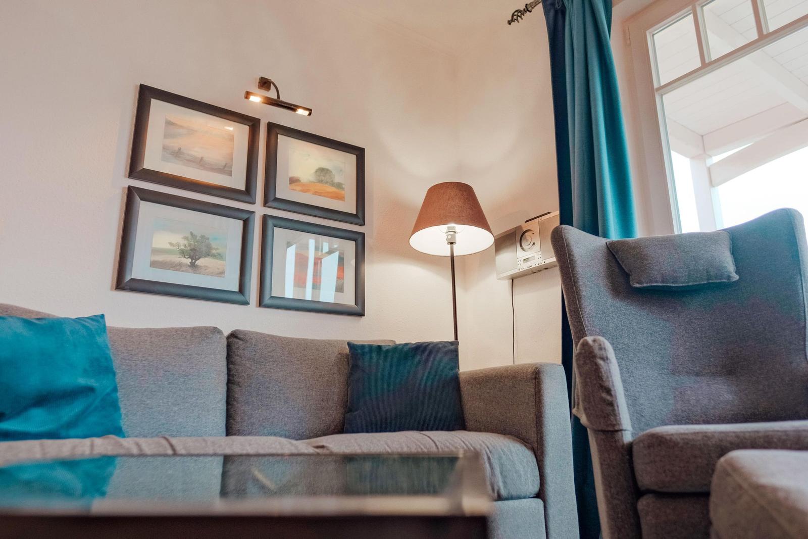 Wohnzimmer mit Sofa, Sessel, Wandbildern und Stehlampe