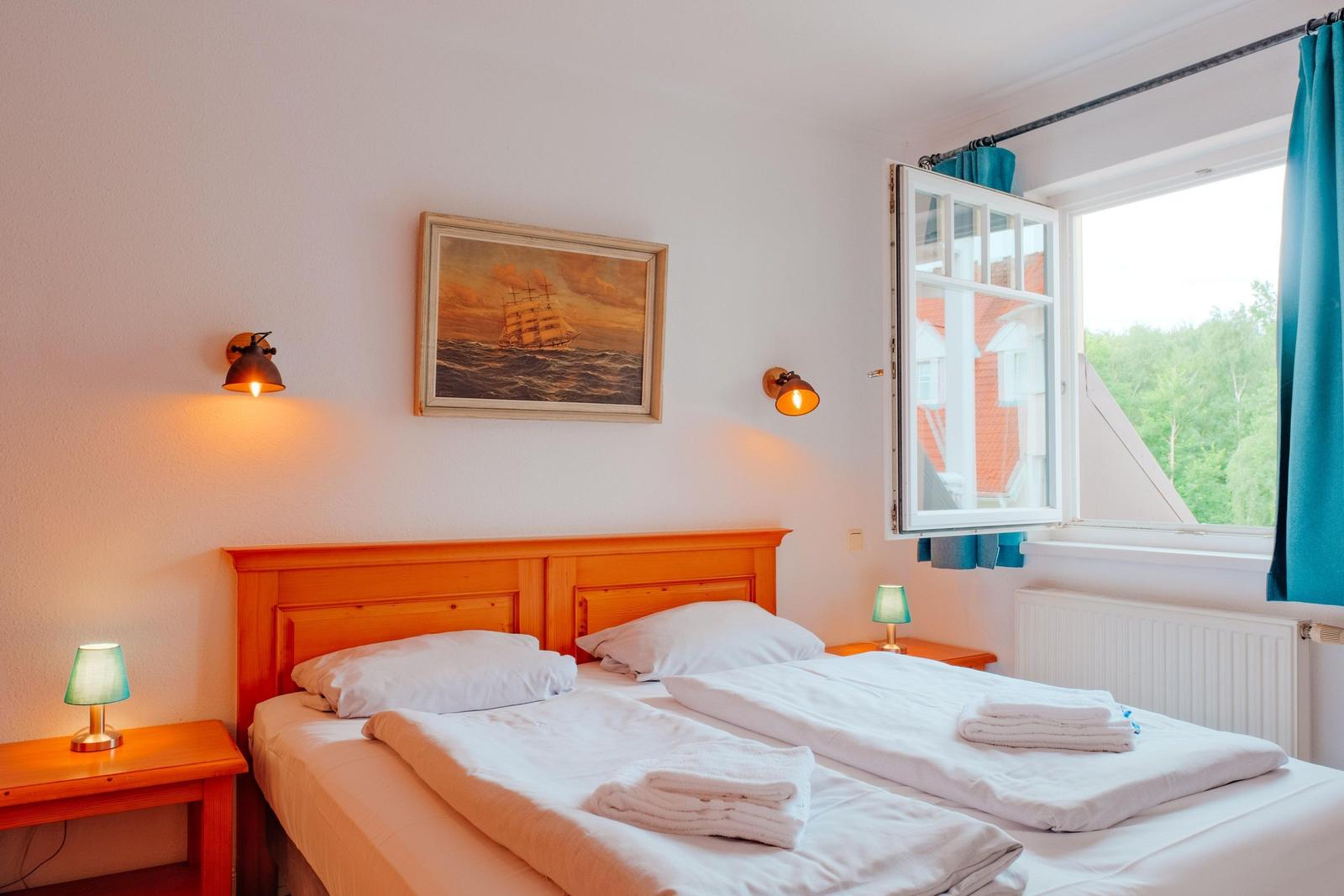 Zimmer mit Doppelbett, Fenster und Wandbild mit Segelschiff.