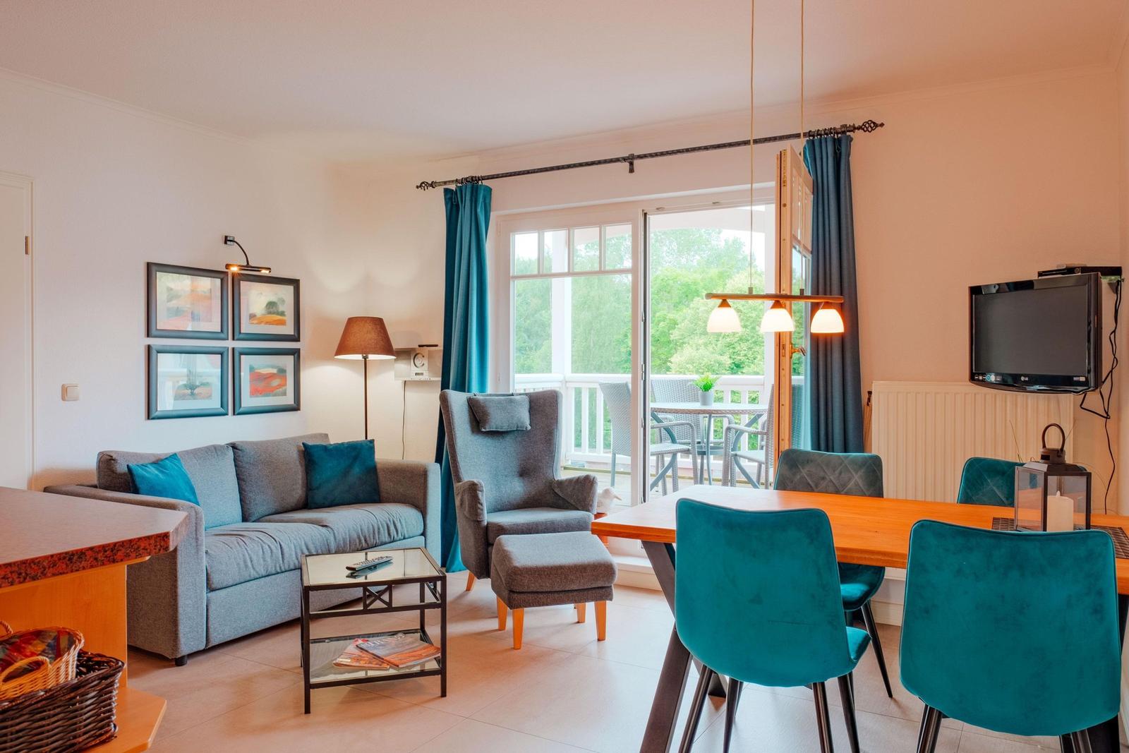 Wohn- und Essbereich mit Sofa, Sessel, Esstisch und Balkonansicht.