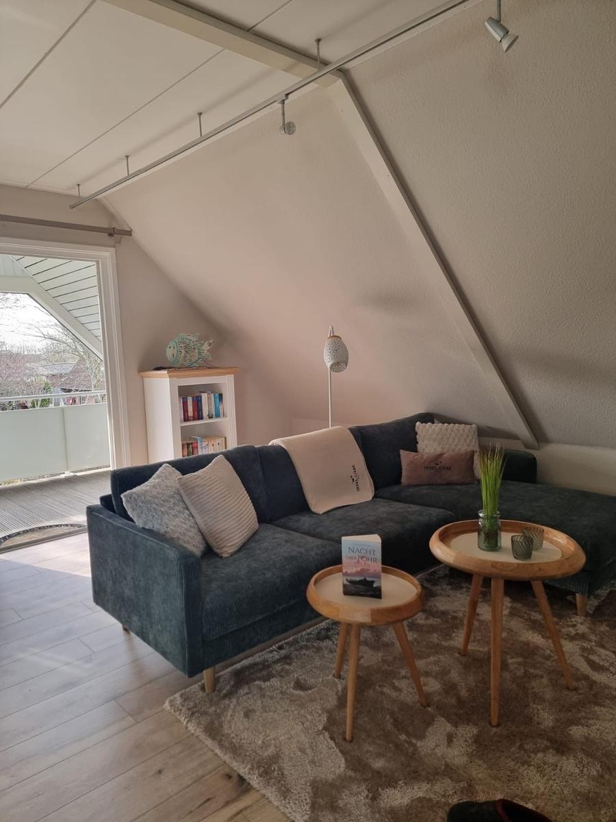 A living room with a dark blue sofa, two round tables, and a bookshelf.