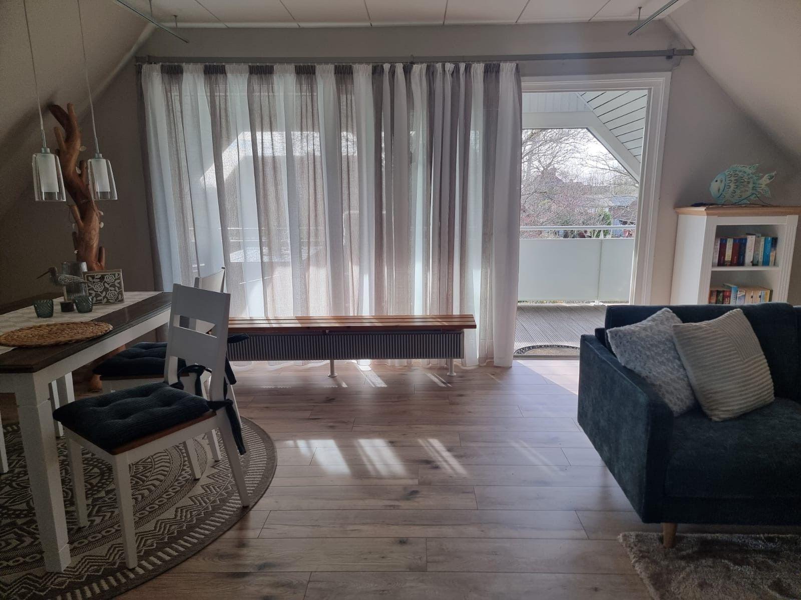 Living area with sofa, table, chairs, and view of balcony.
