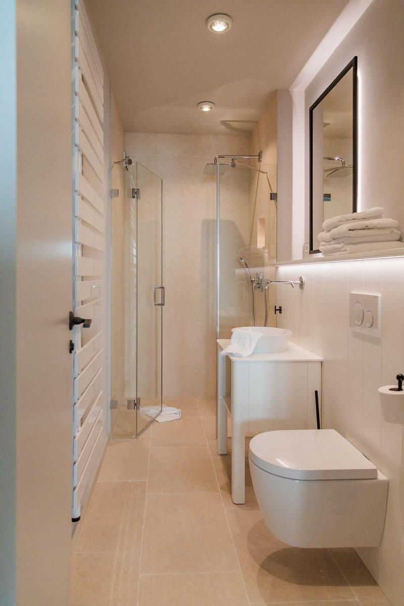 Moderne Dusche mit Glaswand, Waschtisch und Toilette in weißer Ausführung.