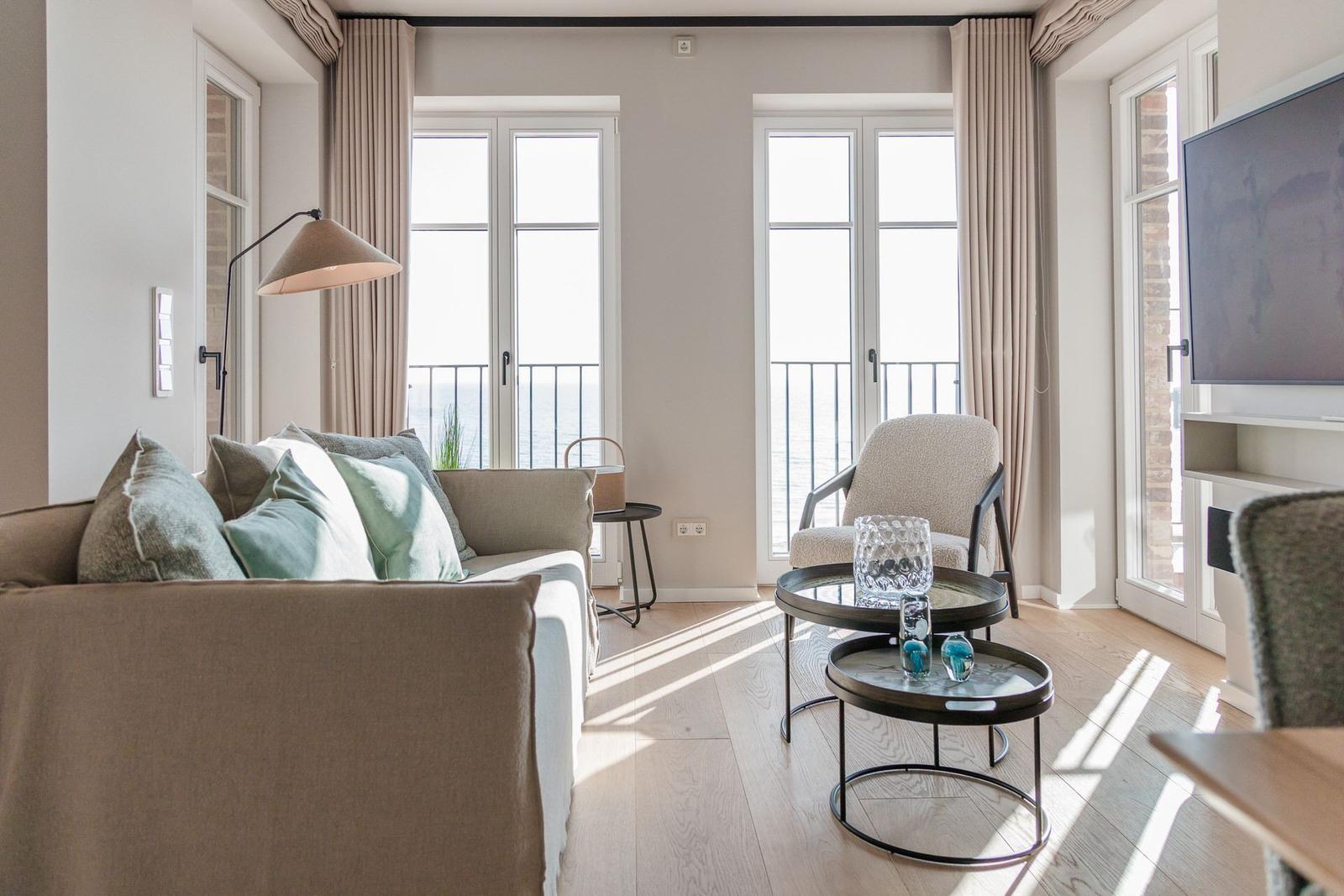 Wohnzimmer mit Sofa, Sitzgelegenheit und Blick aufs Meer.