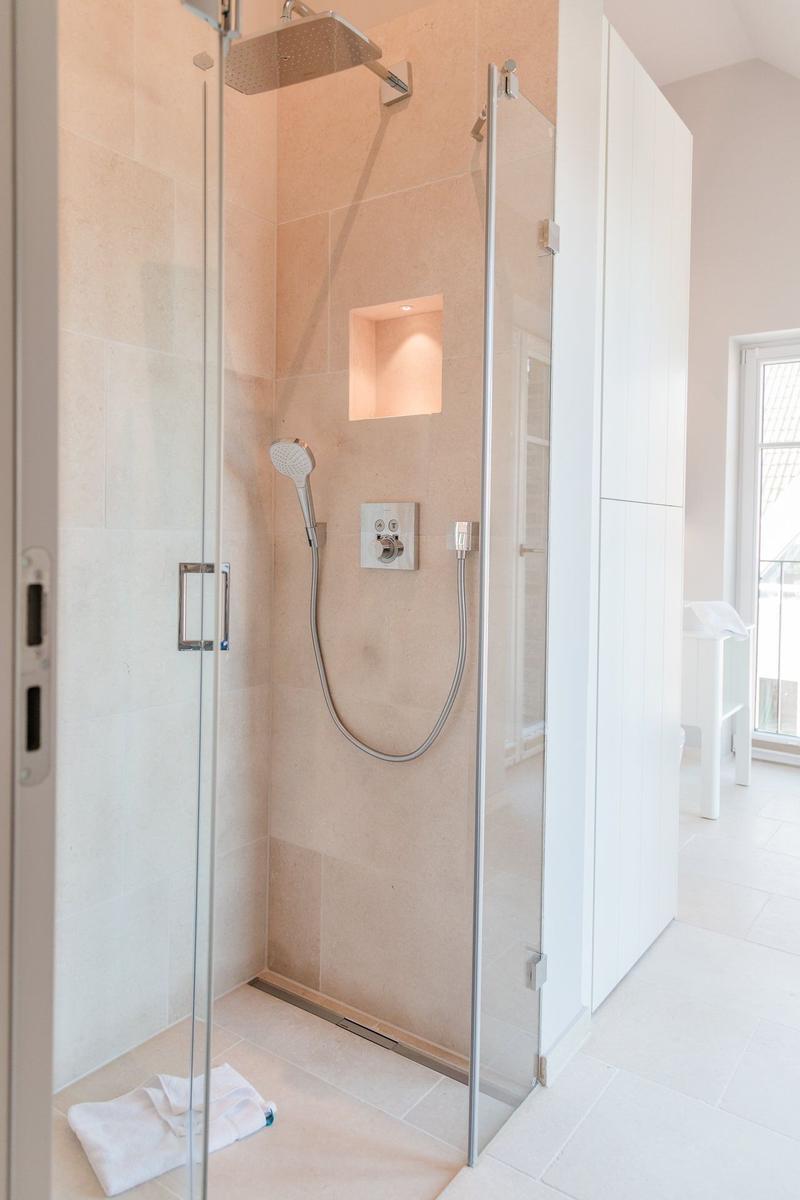 Dusche mit Glaswand, Duschbrause und eingebauter Ablage