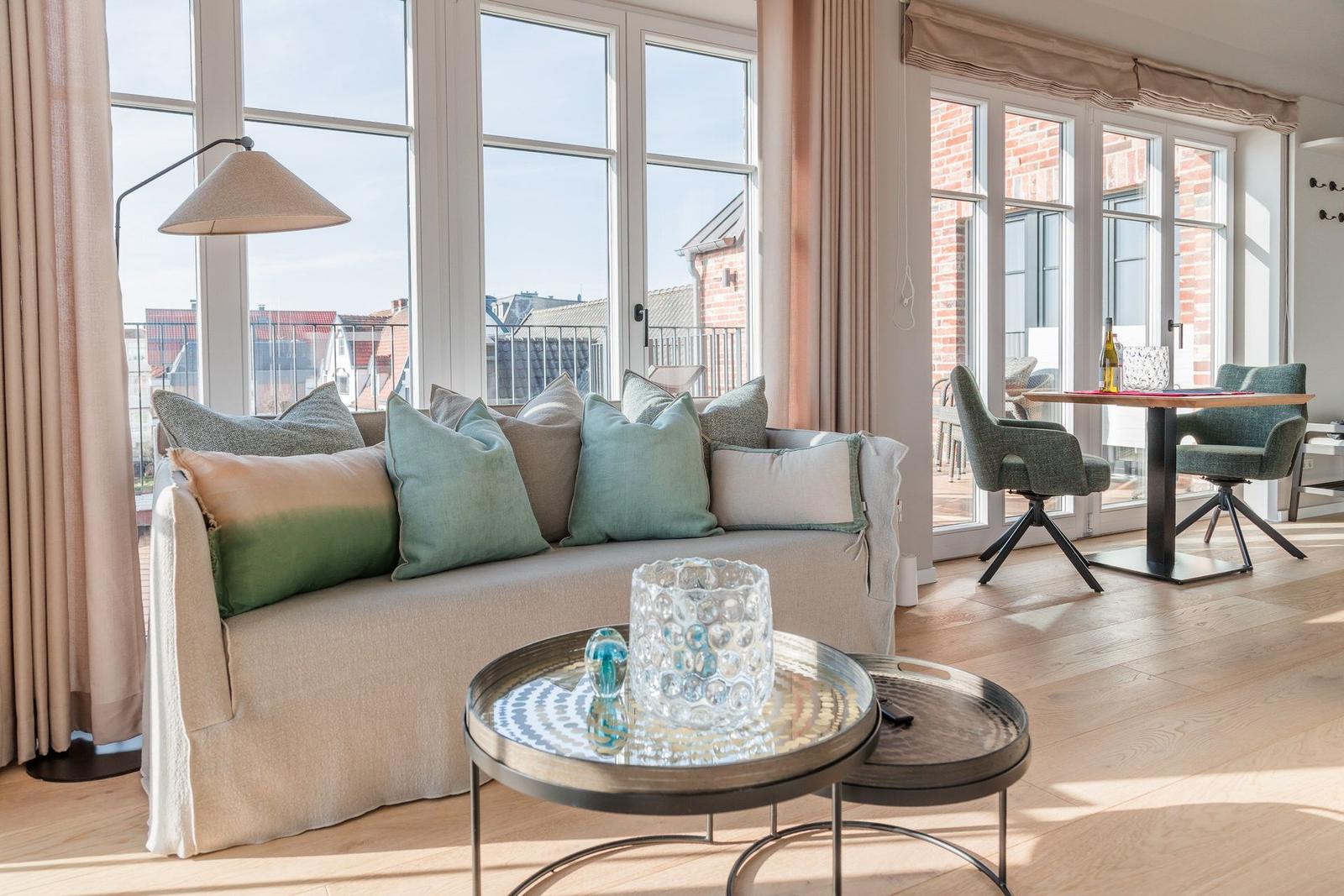 Wohnzimmer mit Sofa, Couchtisch und großem Fensterblick auf Balkon.