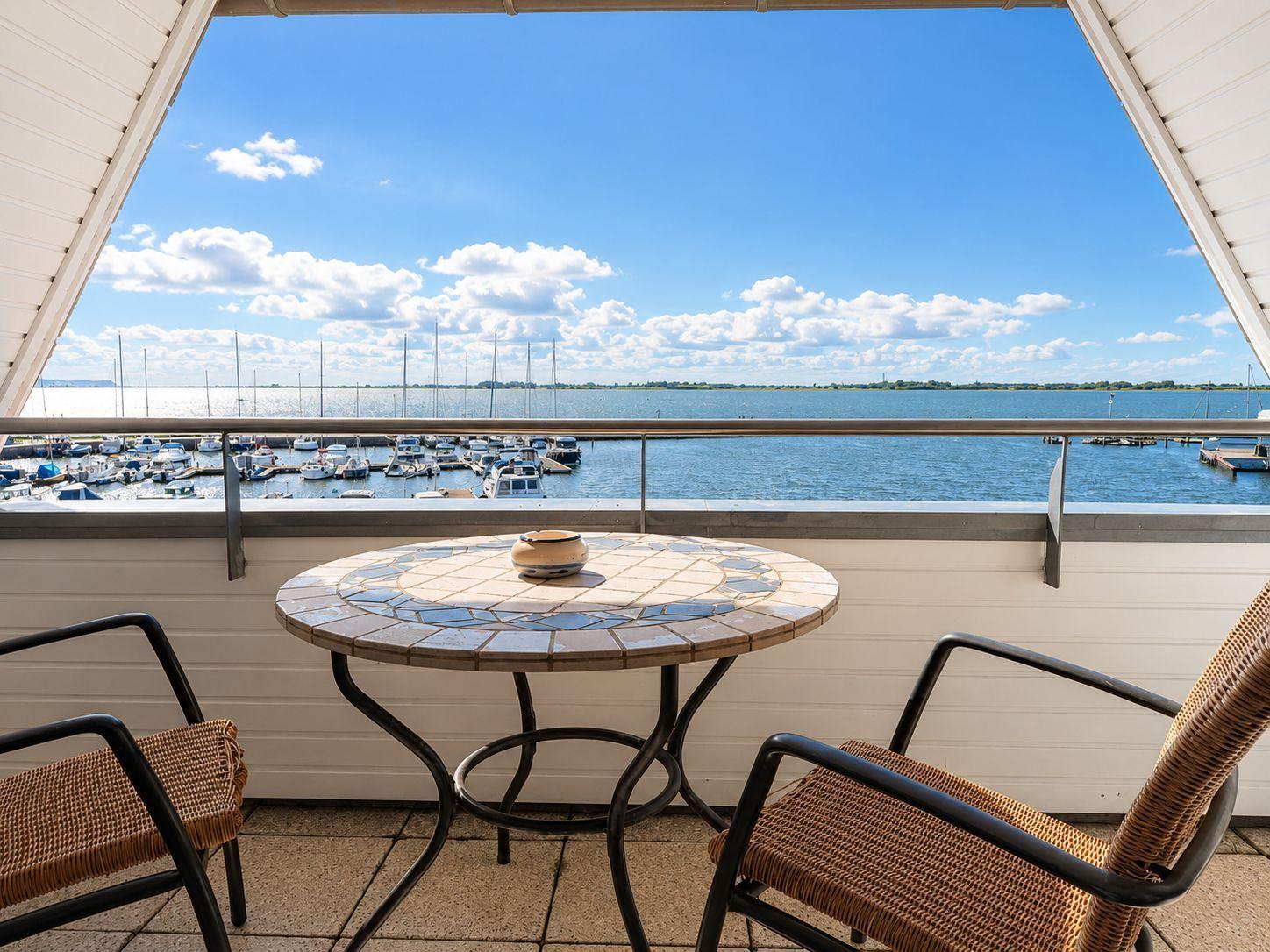 Terrasse mit Tisch und Stühlen bietet Blick auf Hafen mit Booten.