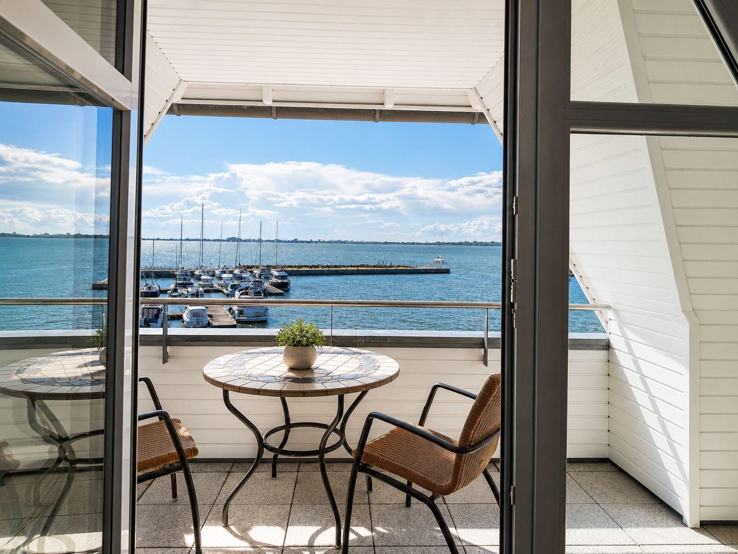 Terrasse mit Tisch und Stühlen bietet Blick auf Hafen mit Booten.