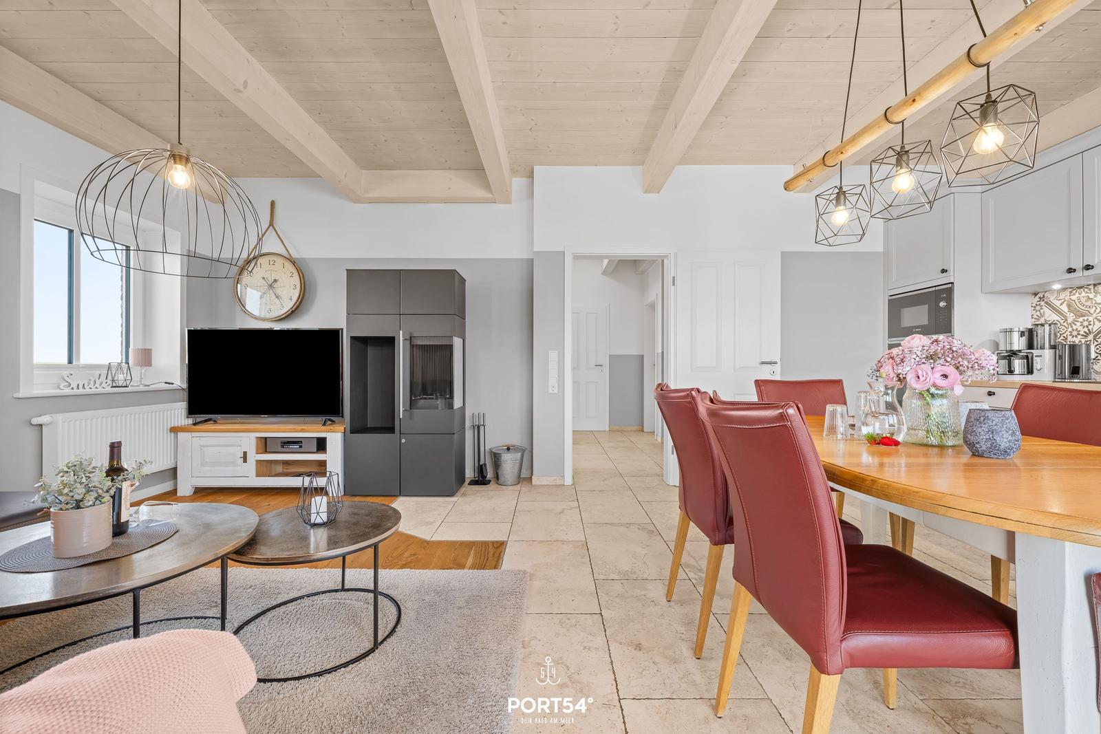 Living and dining area with wooden floor, red chairs, and kitchen.