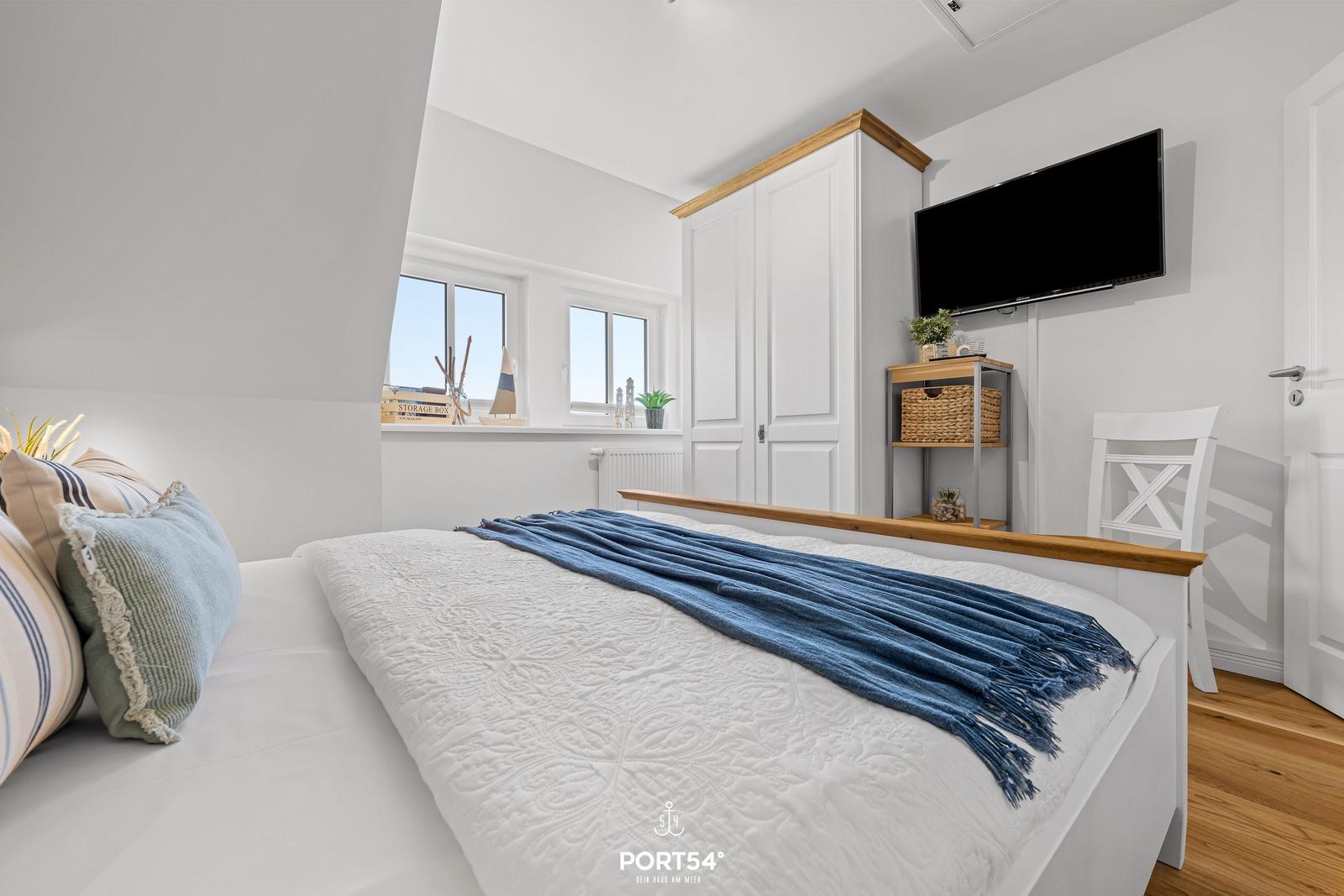 Bedroom with bed, wardrobe, and TV mounted on the wall.