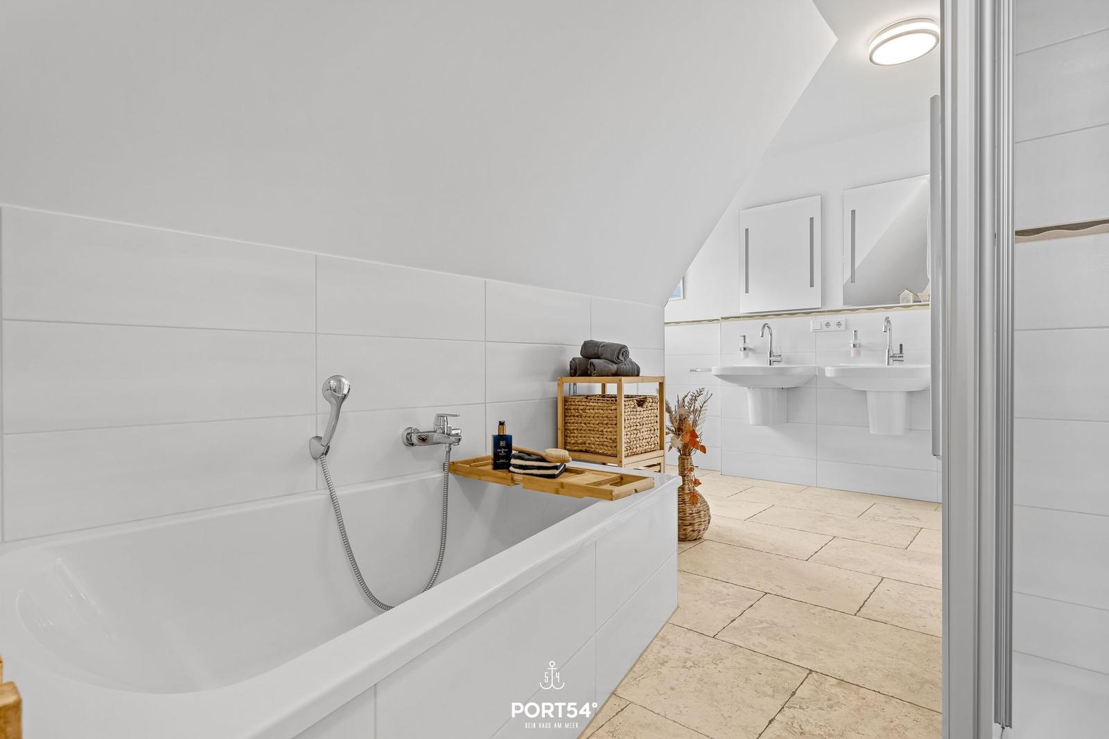Shower, bathtub, and two sinks in white surroundings.