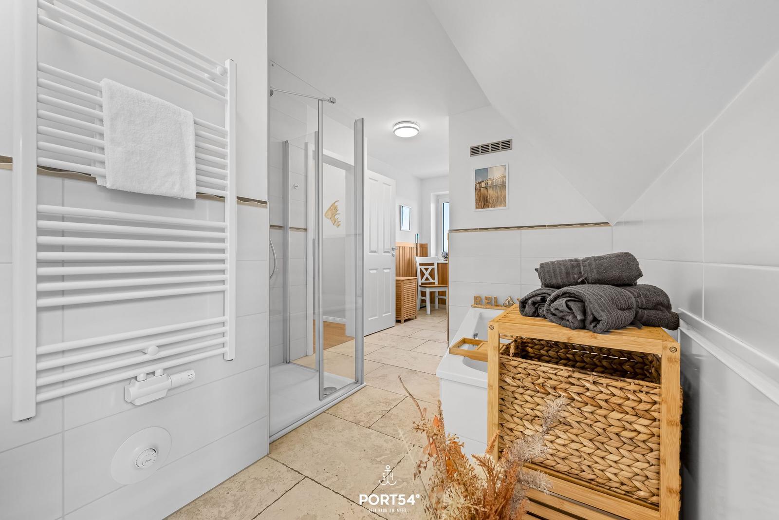 Bathroom with shower, towel rack, and laundry basket.