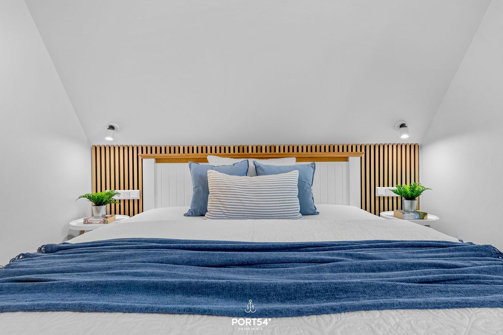 Bedroom with bed, wooden headboard, and plants on nightstands.