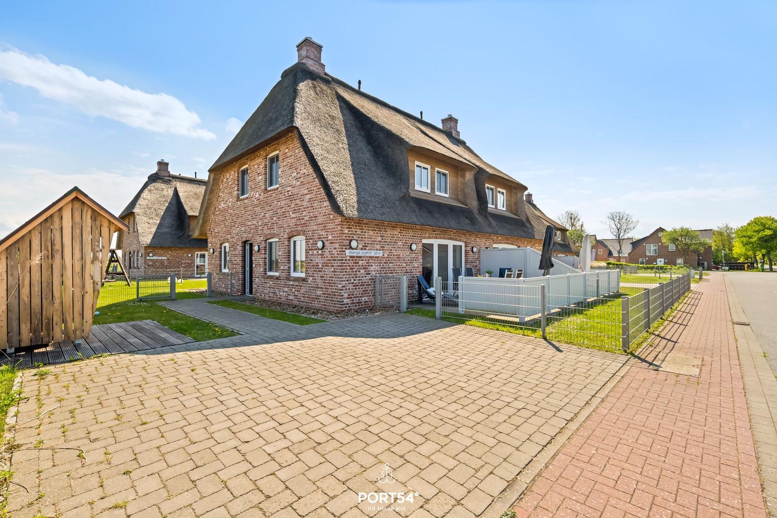 House with thatched roof, paved yard, and garden area with seating.