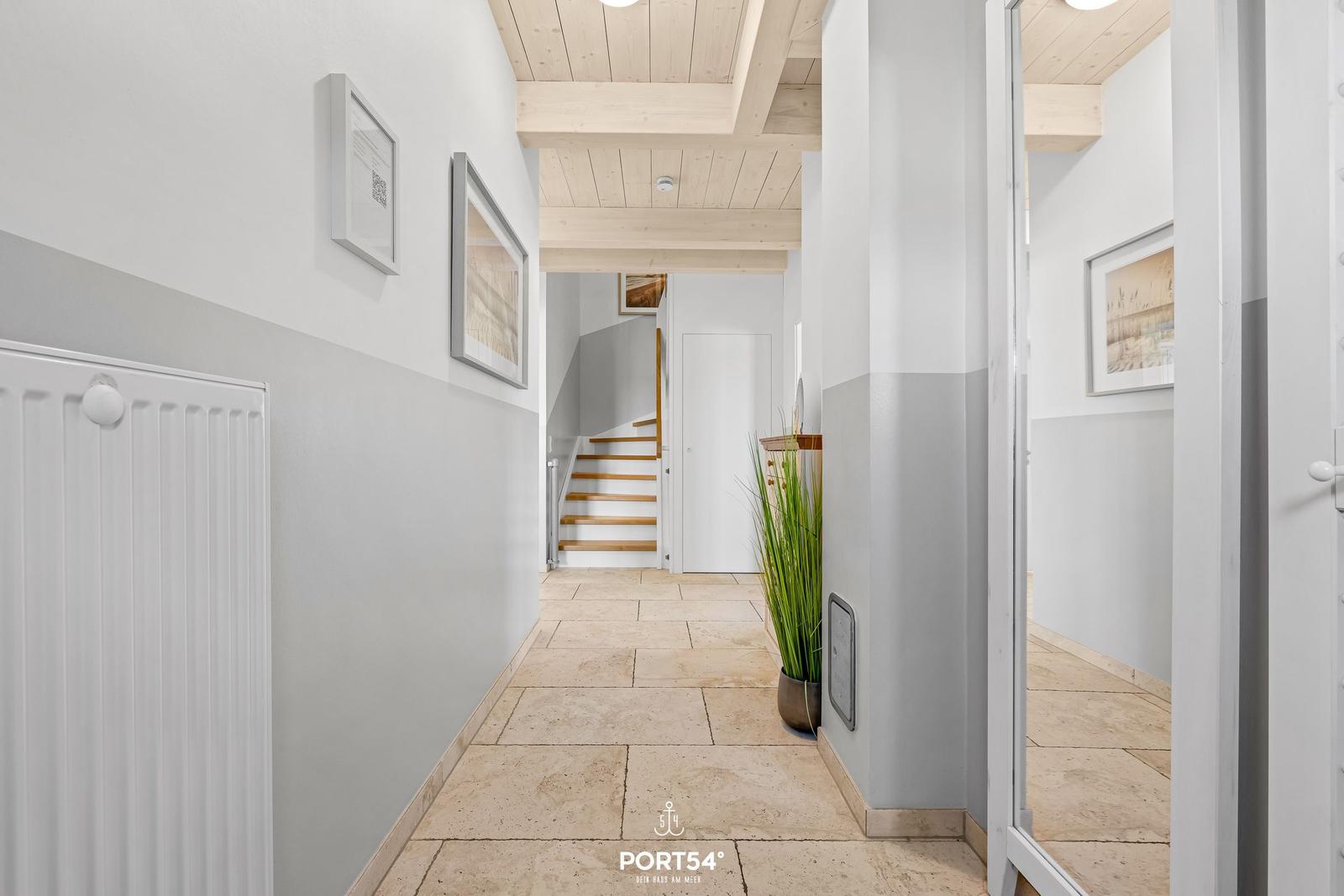 Hallway with stone floor, wooden ceiling, and staircase in the background.