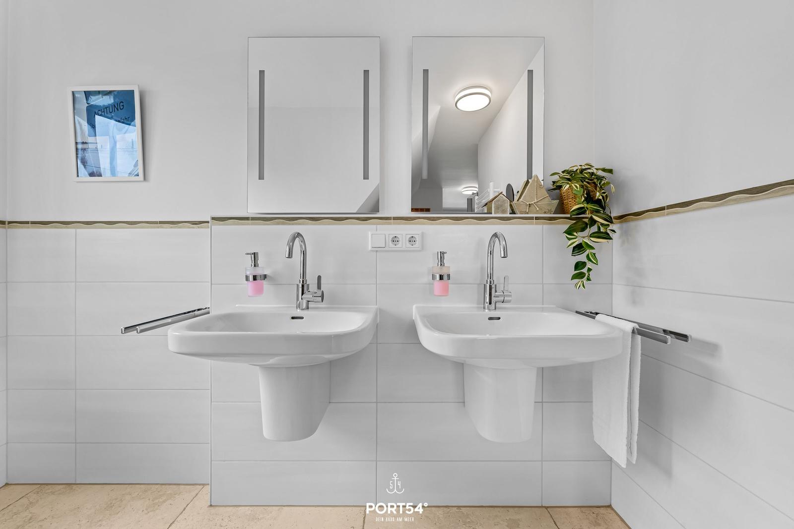 Zwei Waschbecken mit Spiegeln und Handtuchhaltern an der Wand.