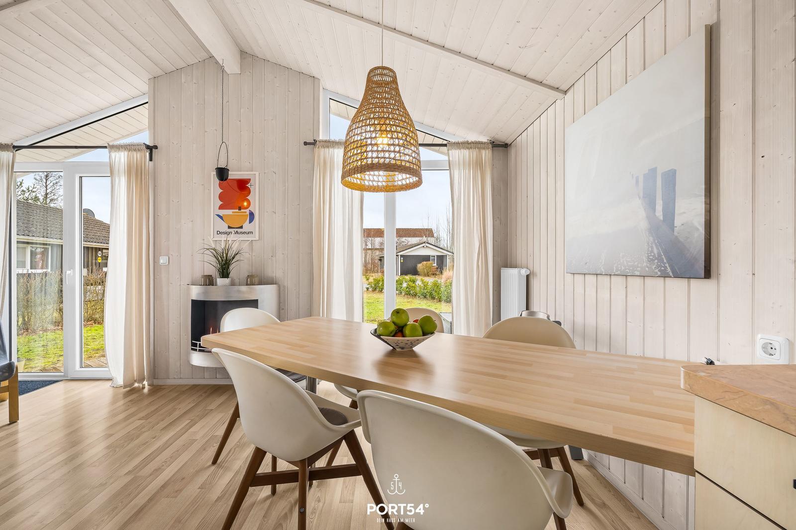Essbereich mit Holztisch, Stühlen und Fenstern. Decke und Wände sind mit Holz verkleidet.