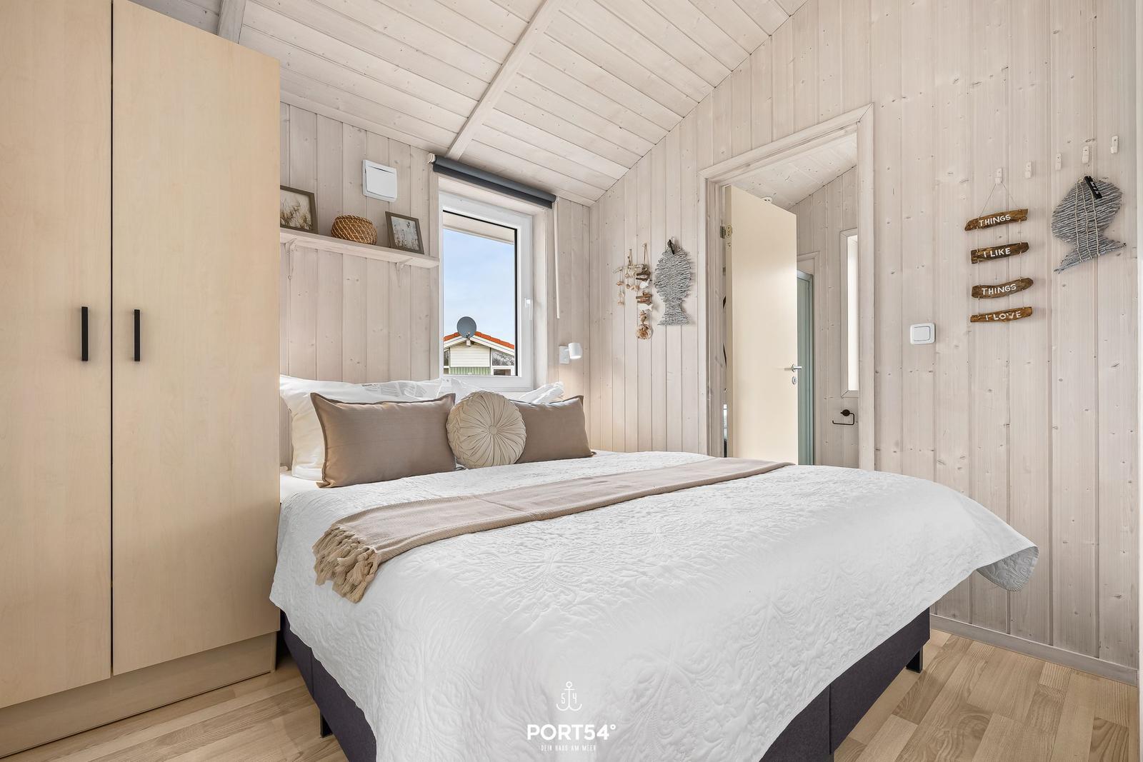 Schlafzimmer mit Bett, Kleiderschrank und Fenster zur Aussicht.
