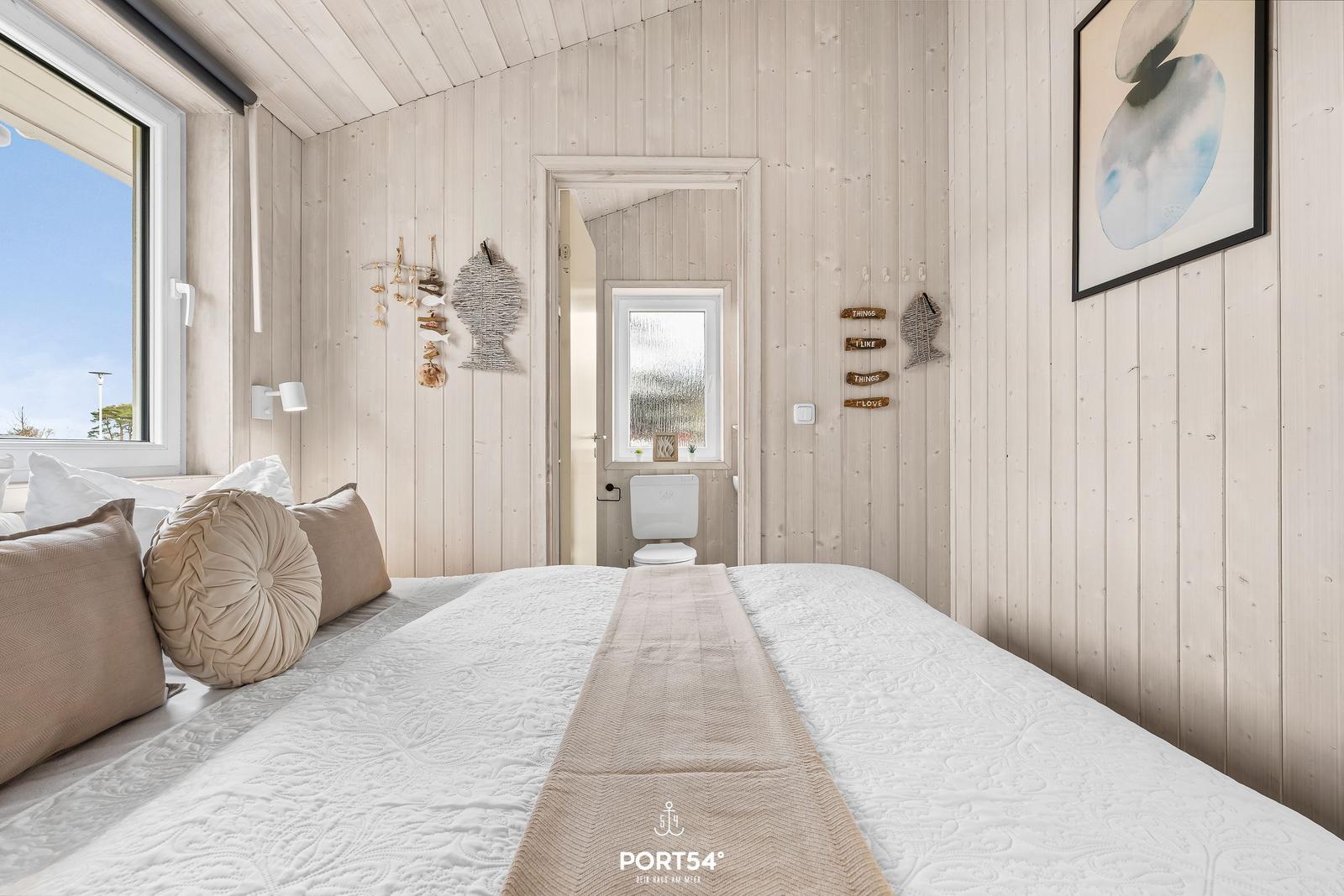 Schlafzimmer mit Holzwand, Bett und Blick auf den Himmel.
