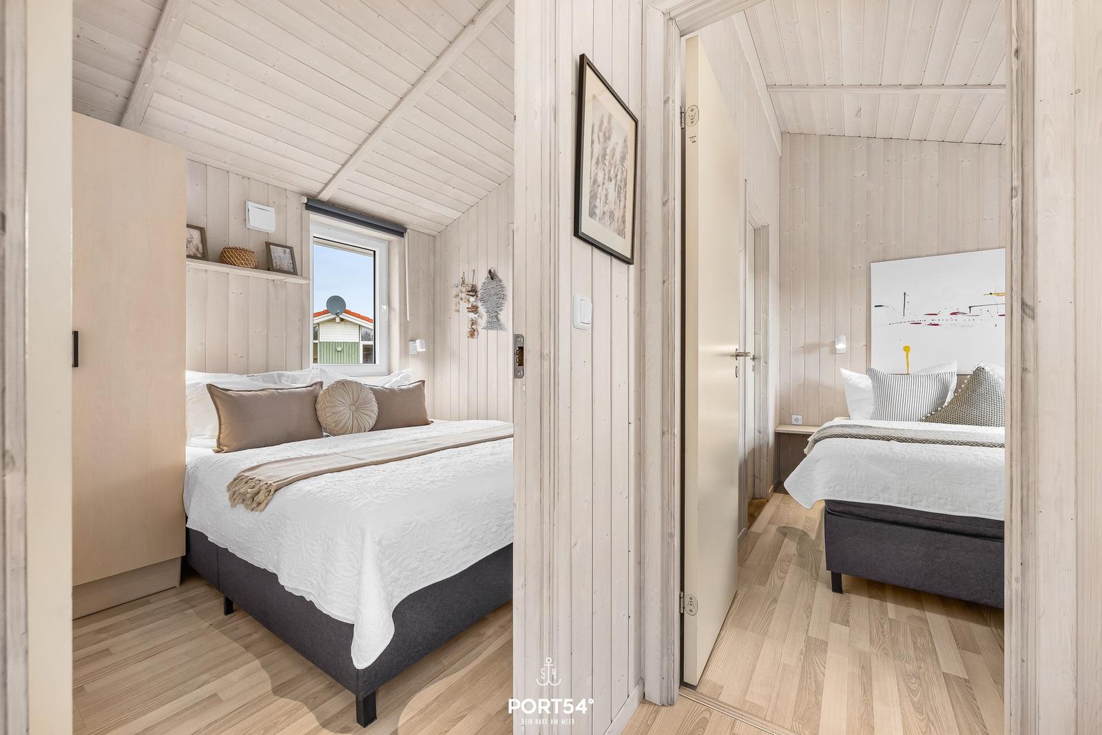 Zwei Schlafzimmer mit Holzwänden und Betten. Eines hat ein Fenster mit Blick.