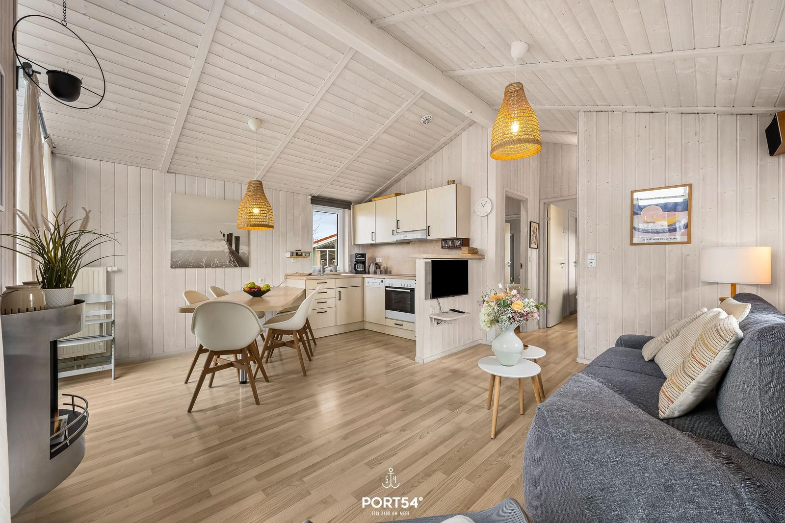 Wohnung mit Essbereich, Küche und Wohnzimmer. Holzdielenboden und weiße Wände.