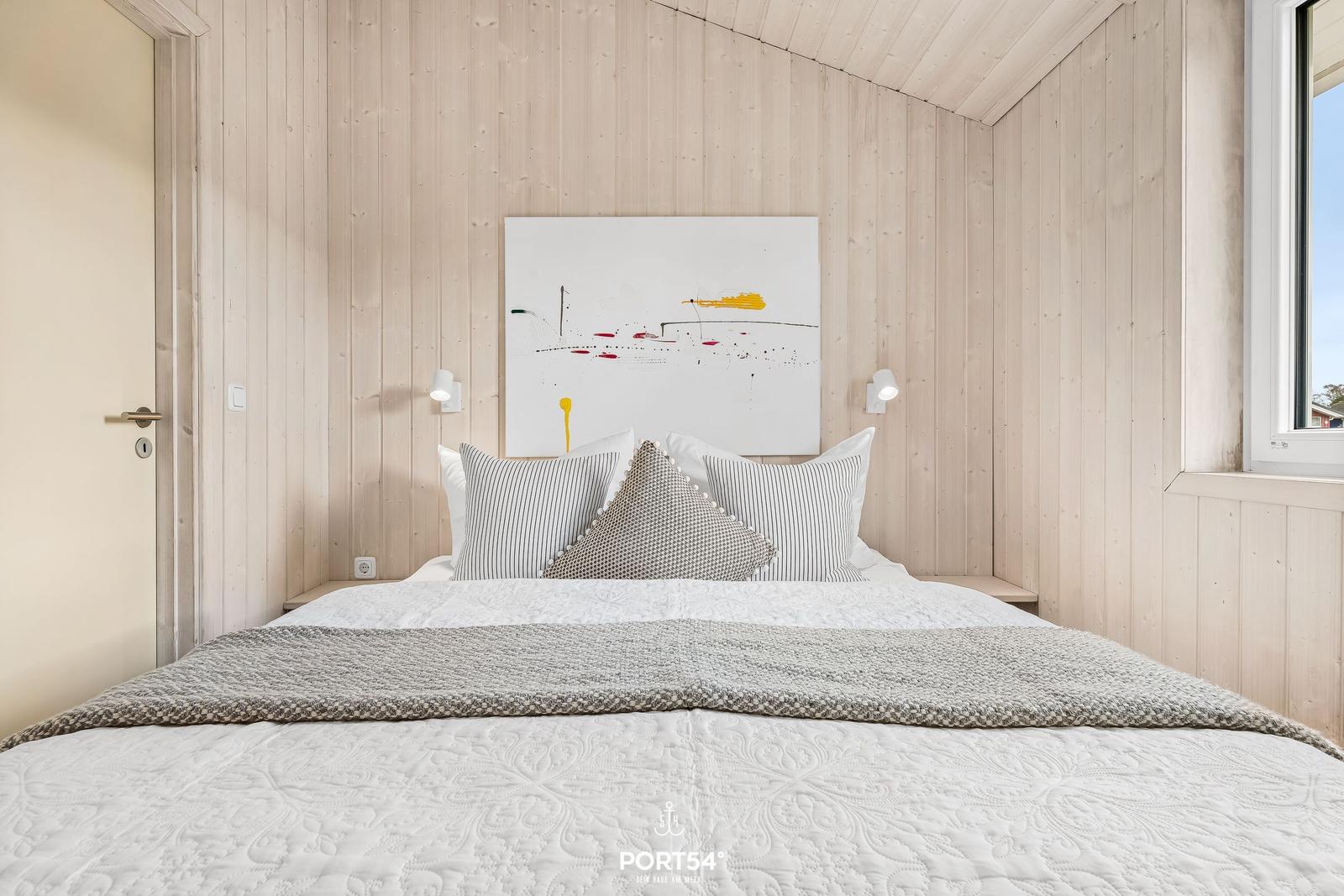 Schlafzimmer mit Holzwand, Bett und Wandbild.