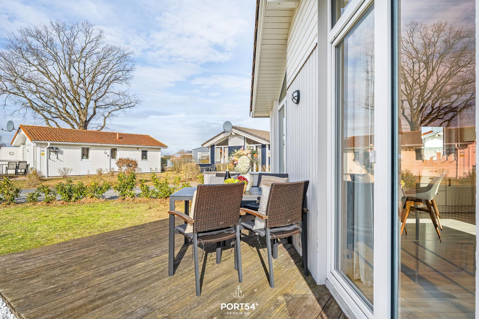 Terrasse mit Tisch und Stühlen, Blick auf Garten und Nachbarhäuser.