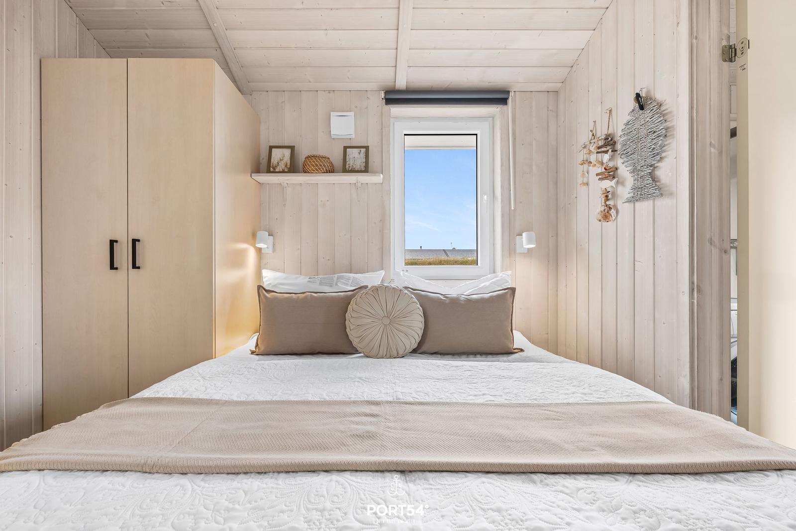 Schlafzimmer mit Bett, Kleiderschrank und Fenster mit Meerblick.