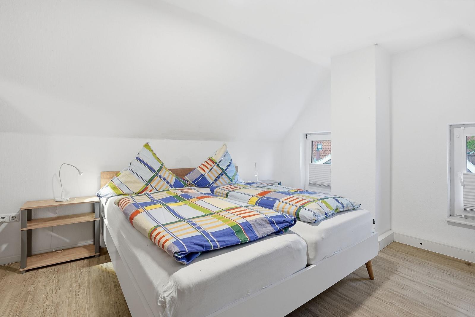 Bedroom with double bed, nightstand, and windows.
