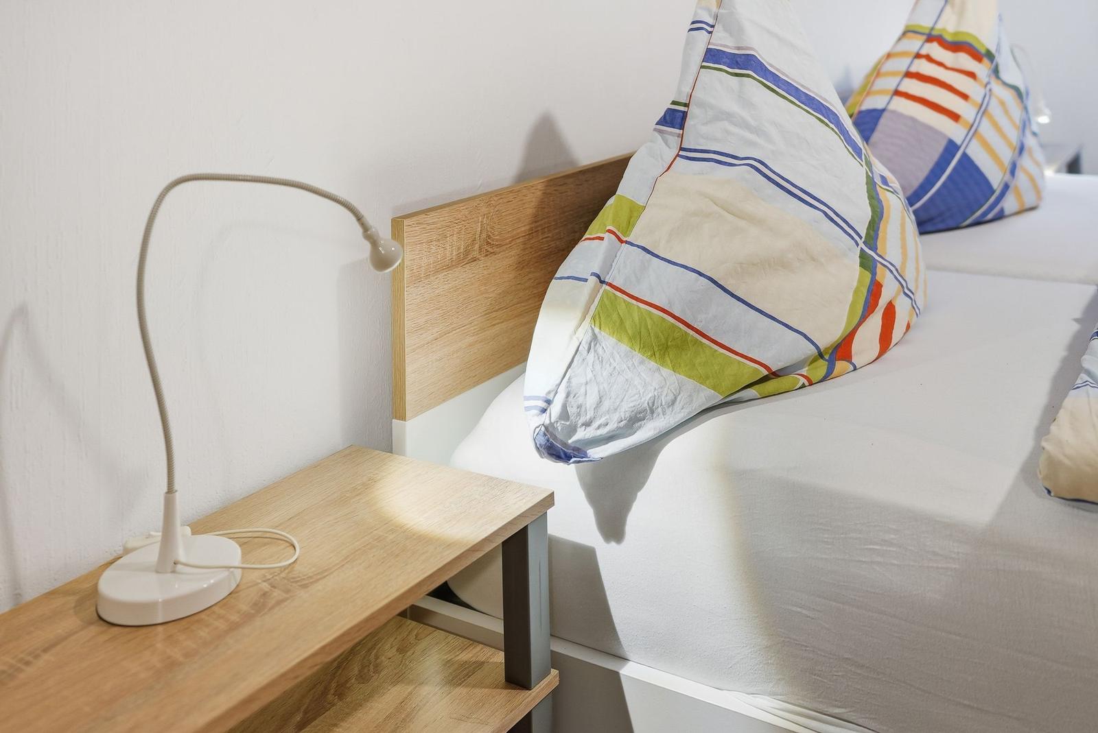 Bedroom with bed, nightstand, and desk lamp.