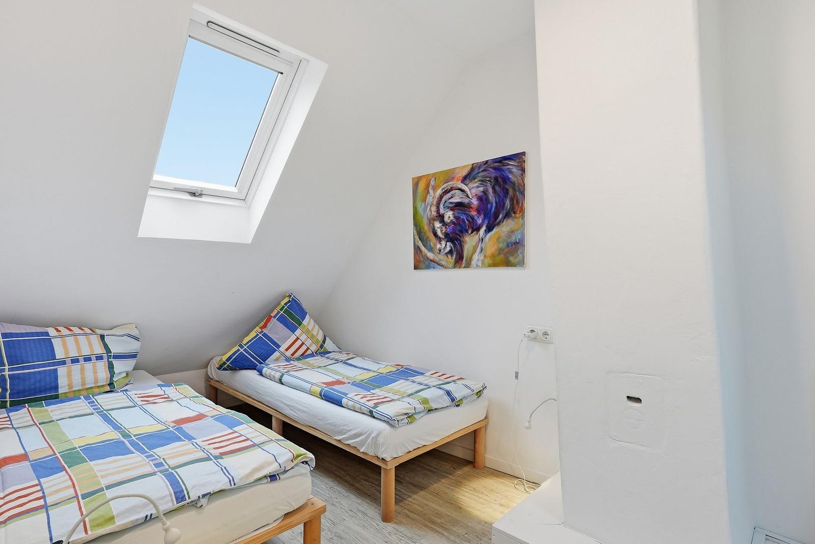 Room with two beds, skylight, and wall art.