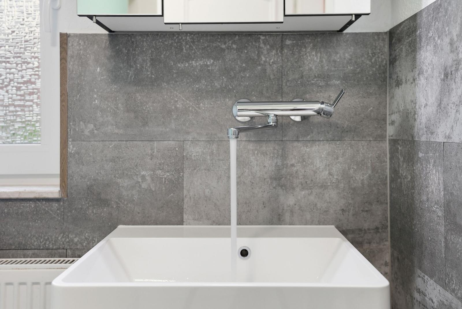 Bathroom with sink, faucet, and gray wall tiles