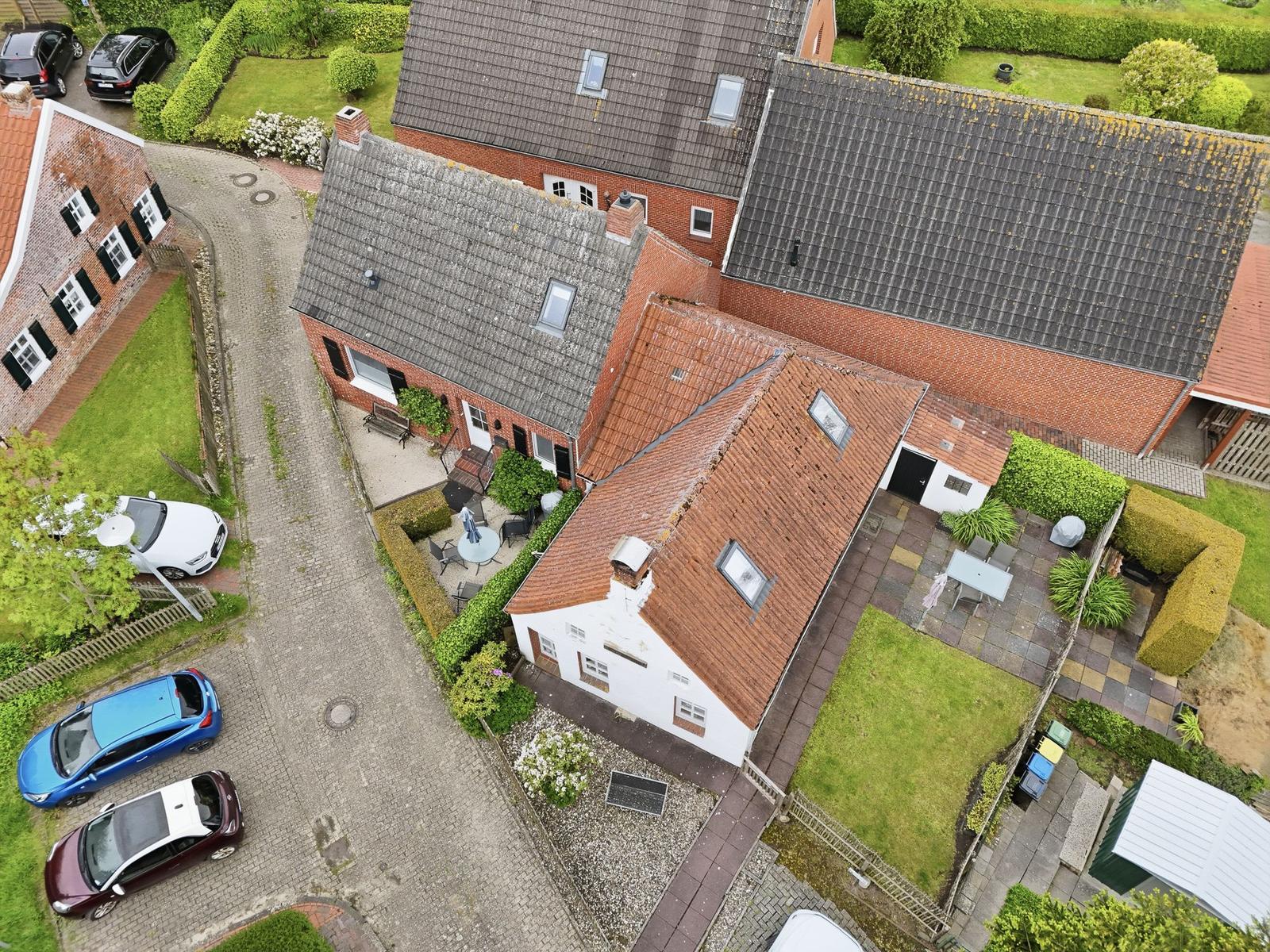 House with garden, terrace and multiple parking spots viewed from above.