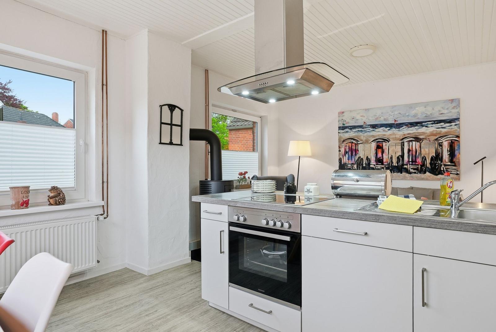 Kitchen with white cabinets, stainless steel stove, and kitchen counter. Windows with view outside.