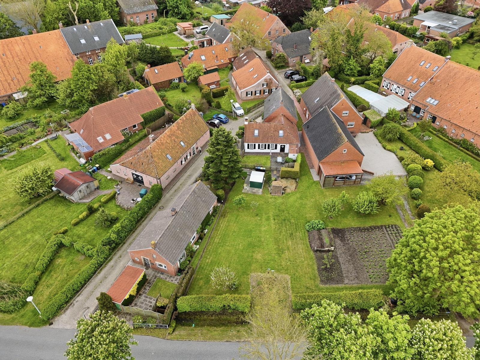 Luftbild von Häusern mit Gärten und Wegen in einer ländlichen Umgebung.