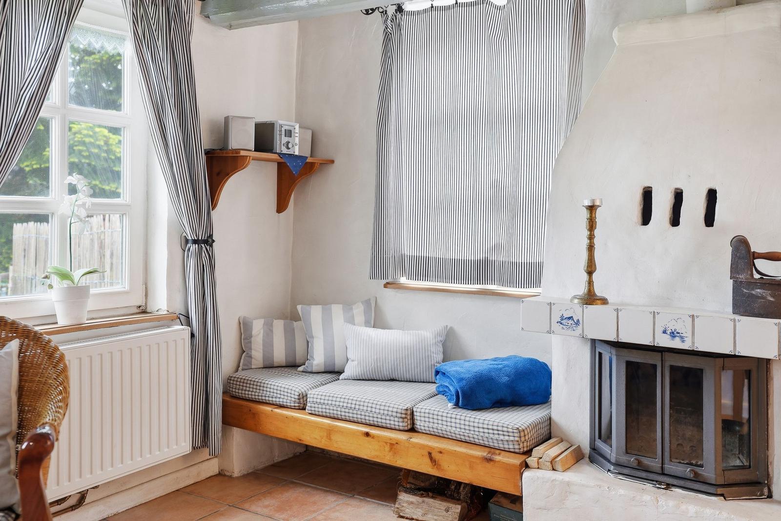 Sitzbank mit Kissen und Handtuch neben Kamin und Fenster mit Vorhängen.