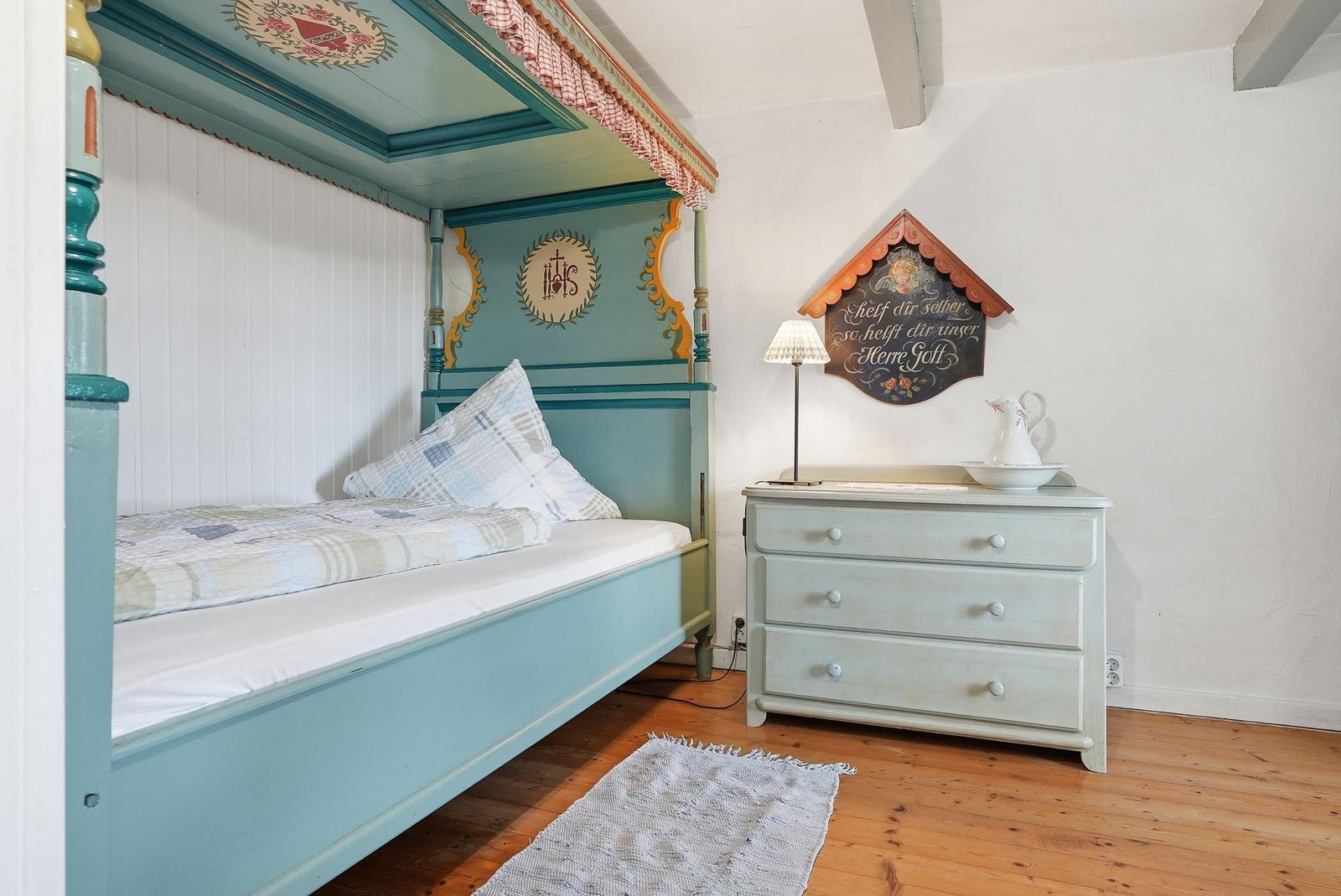 Ein Schlafzimmer mit einem Bett, einem Schrank und einem Teppich auf Holzboden.