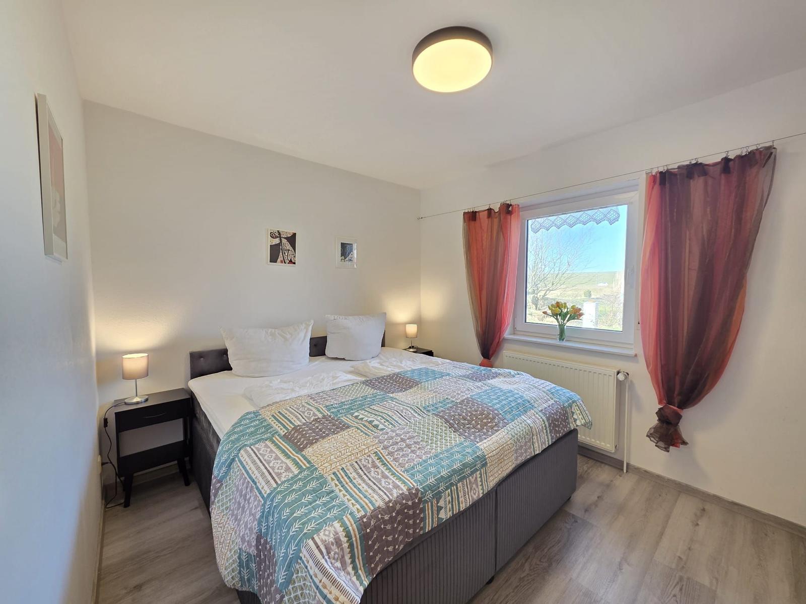 Schlafzimmer mit Doppelbett, Fenster und Holzboden