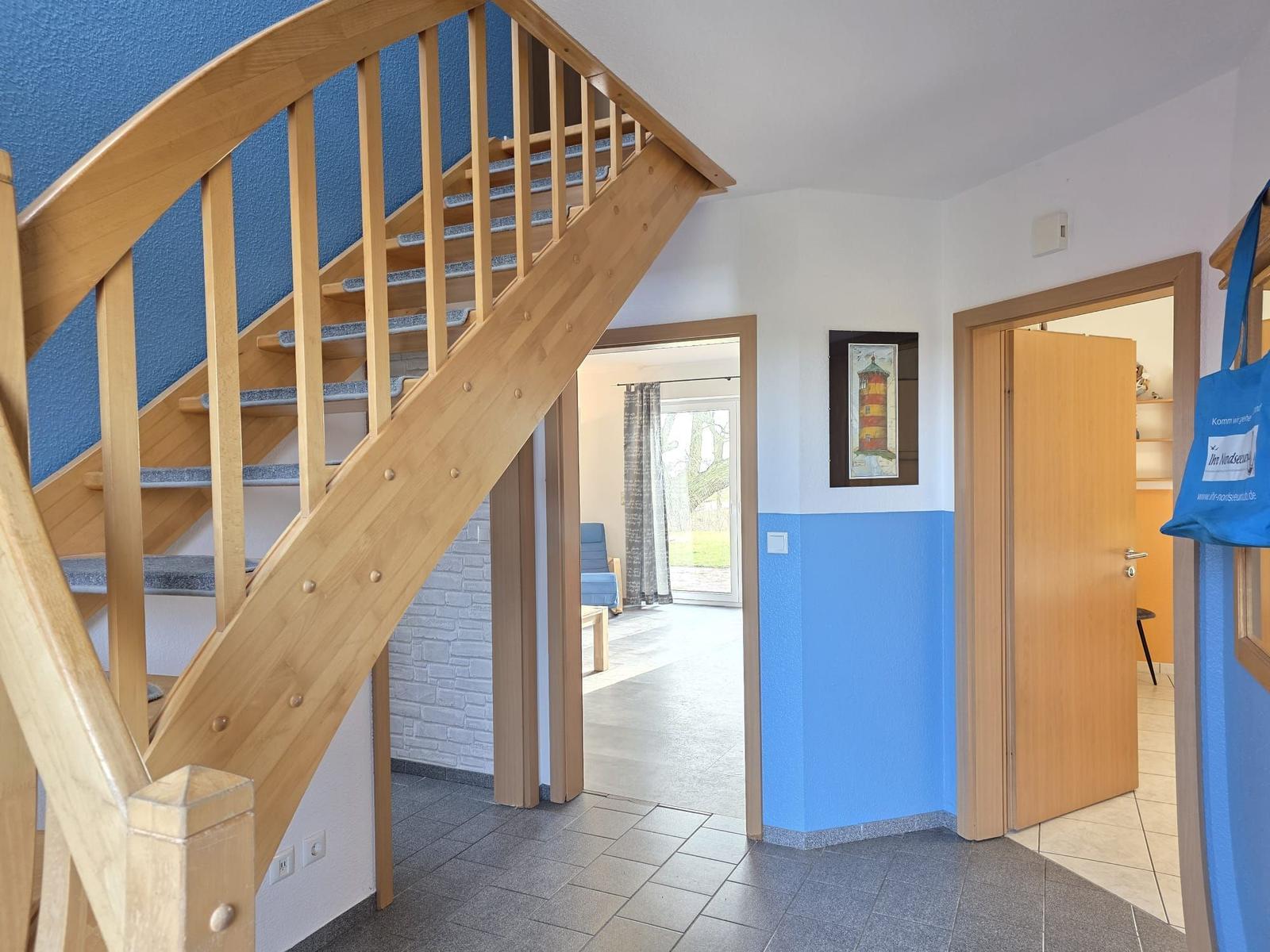 Haus mit Holztreppe, blauen Wänden und Blick in Wohn- und Schlafzimmer.
